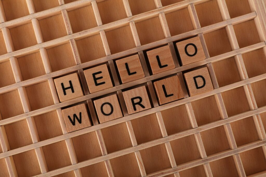 Wooden blocks spell "Hello World" on a wooden grid background. Perfect for programming or coding themes.